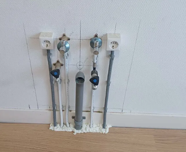 Voorbereiding van waterleidingen, afvoer en elektra op de muur.