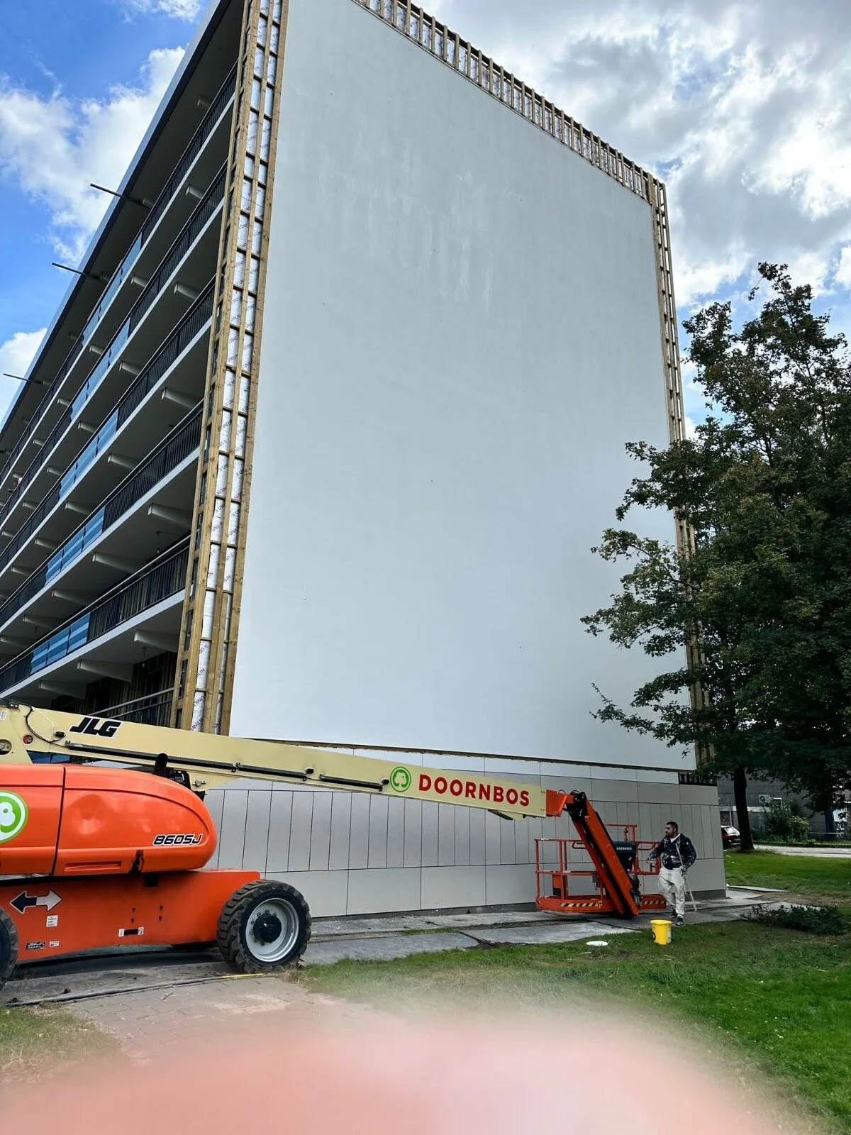 Stucwerk aan de gevel van een flatgebouw met hoogwerker.